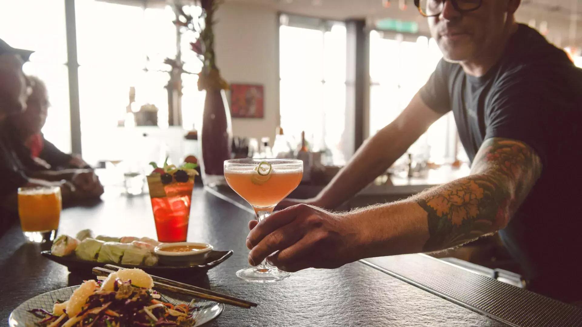 Ein Barkeeper serviert einem Gast einen Cocktail in einer Bar in San Francisco.