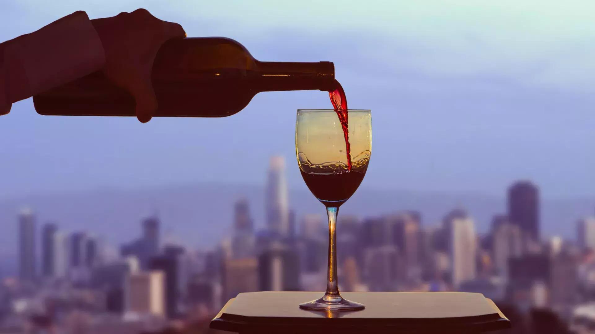 Ein Glas Rotwein wird eingeschenkt, aus dem Fenster ist die Skyline von San Francisco zu sehen.
