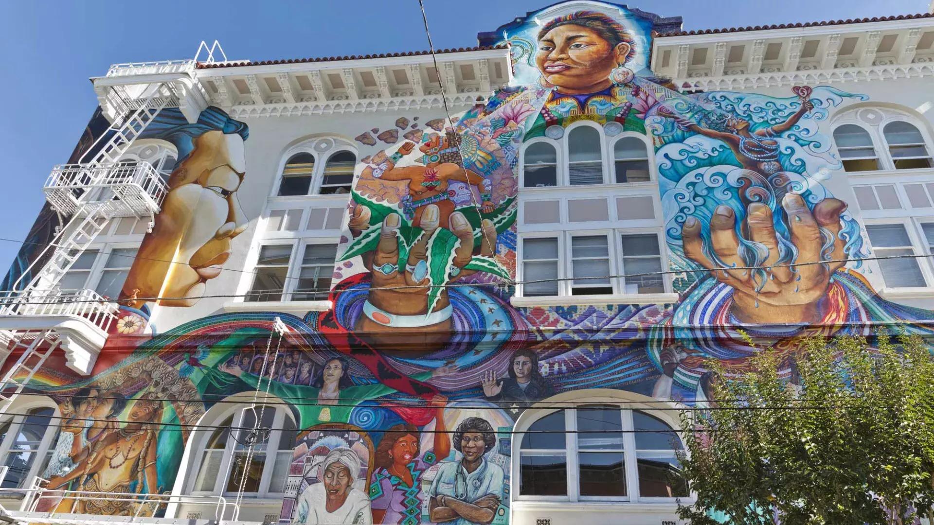 다채롭고 대규모의 벽화가 샌프란시스코 미션 디스트릭트의 여성 빌딩 측면을 덮고 있습니다.