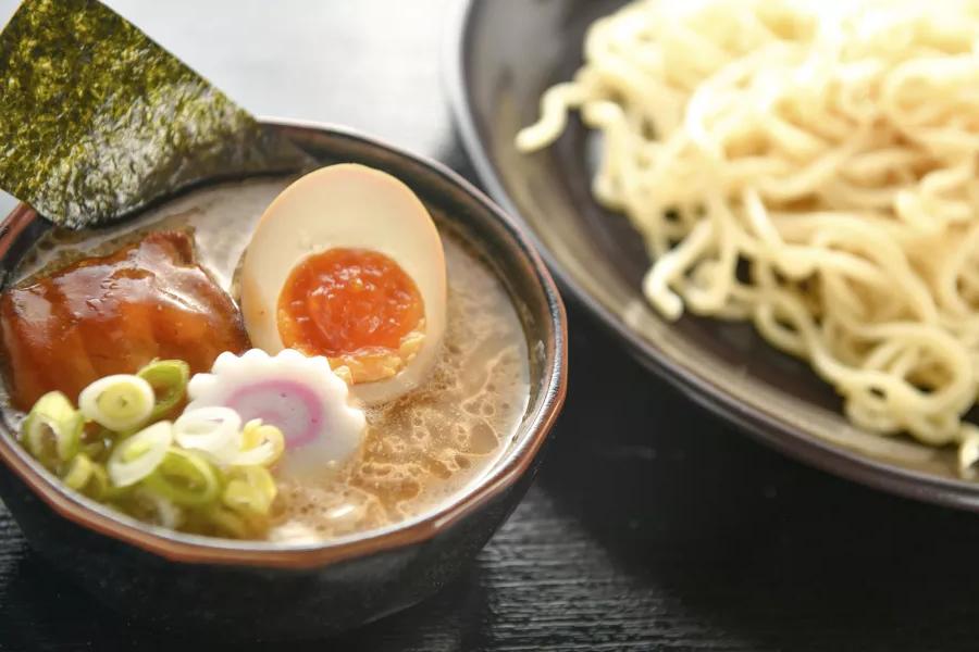 Immagine ravvicinata di una ciotola di noodles e una ciotola di zuppa di ramen con un uovo in camicia, 切成两半.