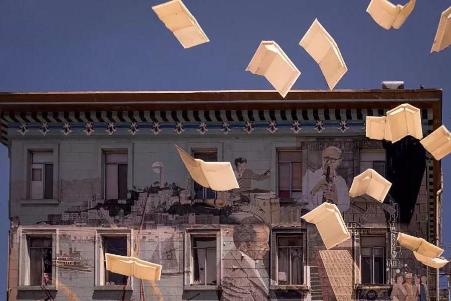 从贝博体彩app的城市之光书店外, 展示一幅壁画的书籍和漂浮的纸.