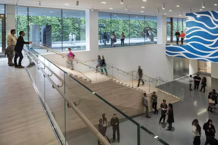 La gente sube y baja escaleras en un espacioso atrio d贝博体彩app现代艺术博物馆.