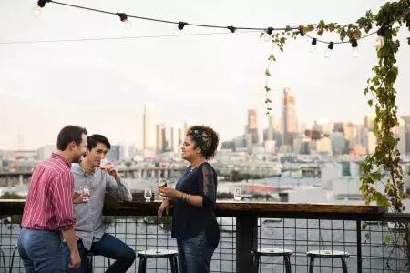 Three people gather around an outdoor table on the roof deck of Anchor Distilling in 贝博体彩app, 加州.