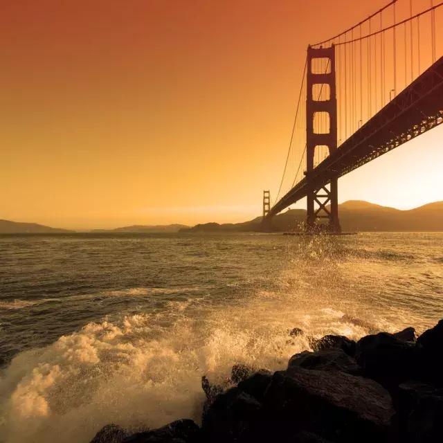 Bei Sonnenuntergang krachen Wellen in der Nähe von Fort Point unter der Golden Gate Bridge.