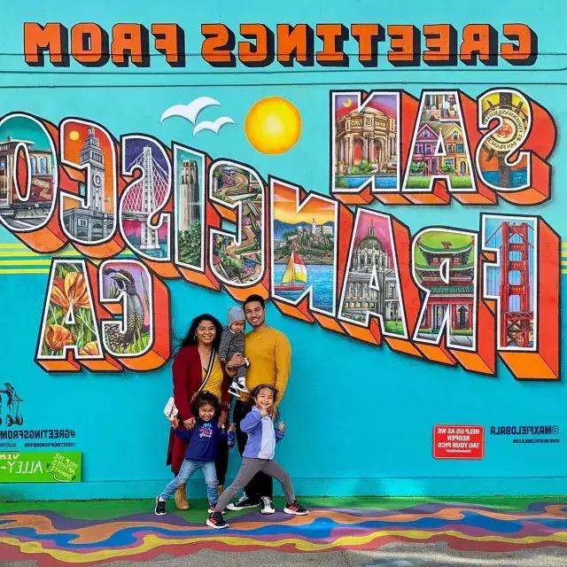 Eine Familie posiert für ein Foto vor einem Wandgemälde in San Francisco