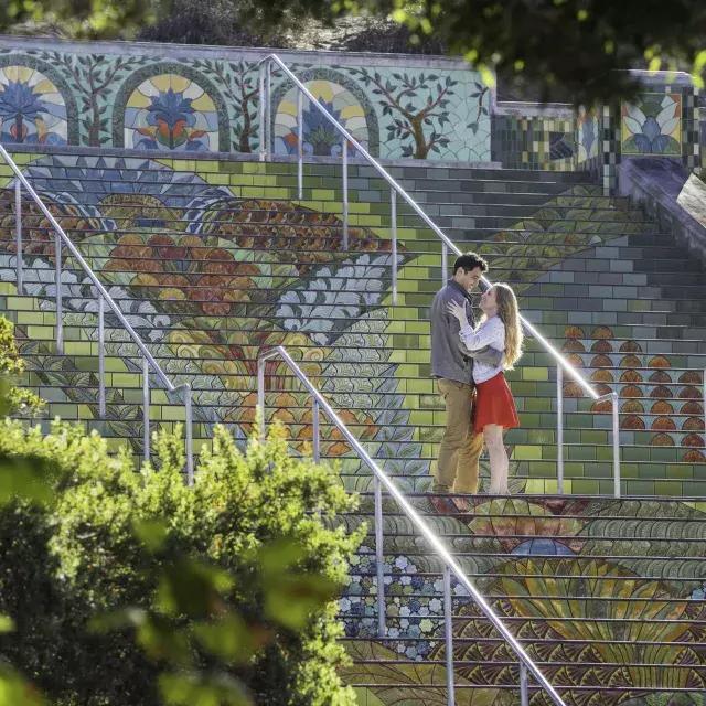Photo taken from an angle of a couple st和ing on Lincoln Park's colorful tiled steps
